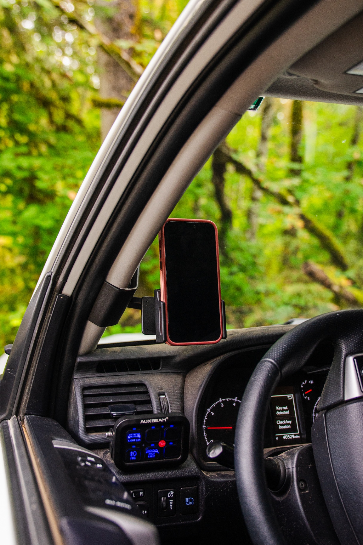 ProClip phone mount holding an iPhone on a 4Runner A-pillar with forest outside